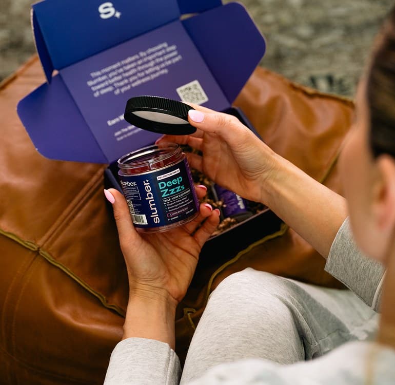 A customer unboxing a Slumber delivery and holding the Deep Zzzs jar